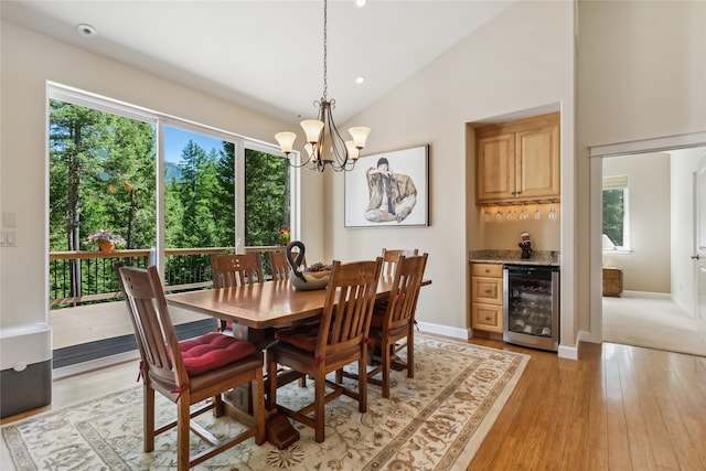 carpeted dining space with high vaulted ceiling, wine cooler, and a notable chandelier