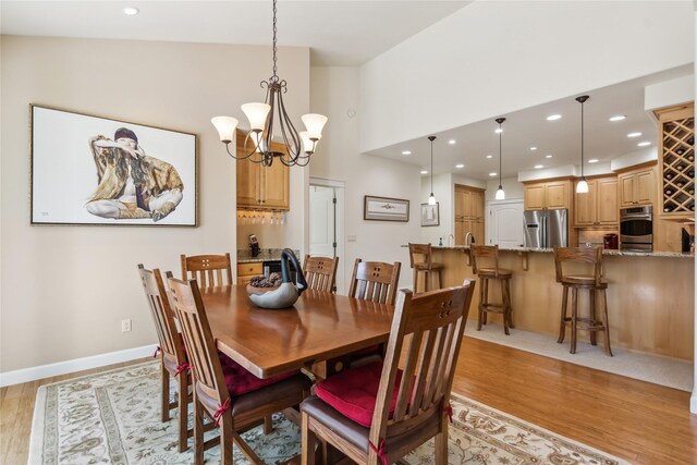 dining room with light wood-type flooring, lofted ceiling, and a chandelier