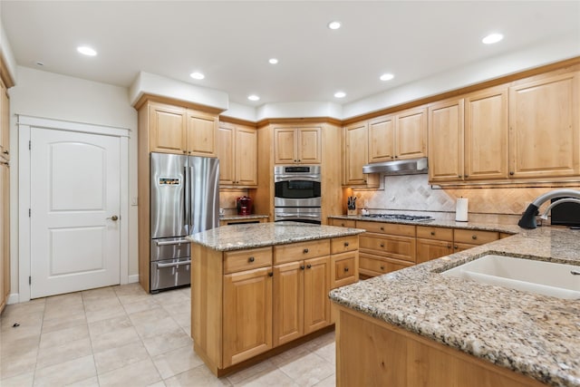 1550 Rolling Ridge Loop, Kalispell, MT 59901 - kitchen featuring stainless steel appliances, under cabinet range hood, light stone counters, a kitchen island, and tasteful backsplash