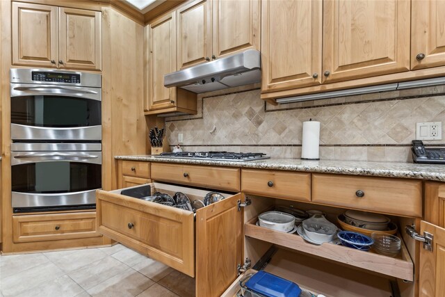 kitchen with stainless steel appliances, light stone counters, decorative backsplash, and light tile patterned flooring