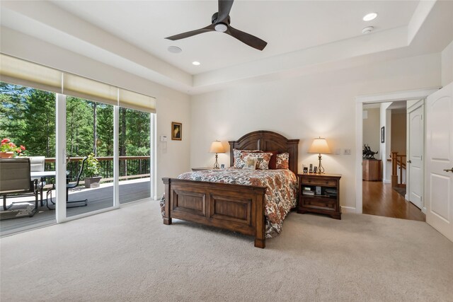 carpeted bedroom with ceiling fan, a tray ceiling, and access to outside