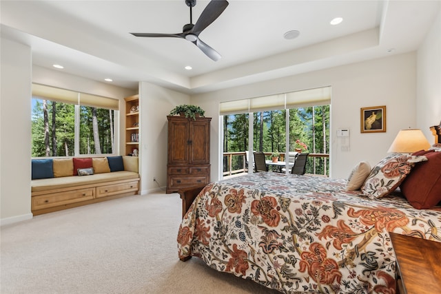 bedroom with a raised ceiling, ceiling fan, carpet floors, and access to outside