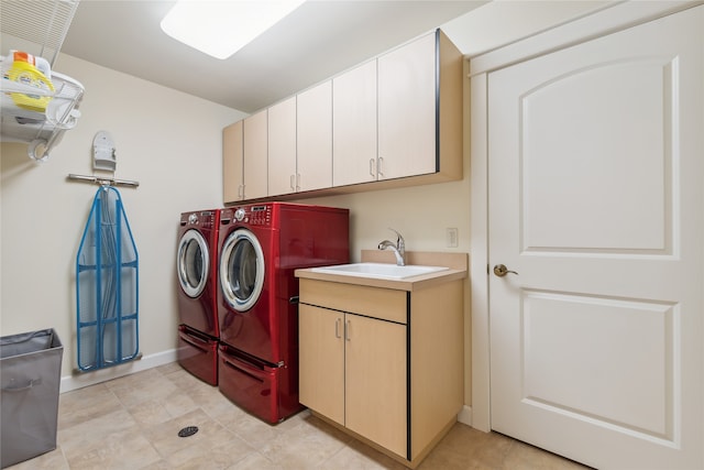 laundry area featuring light tile patterned floors, washer and dryer, cabinets, and sink