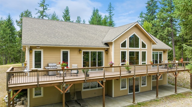 back of property featuring a wooden deck and a patio