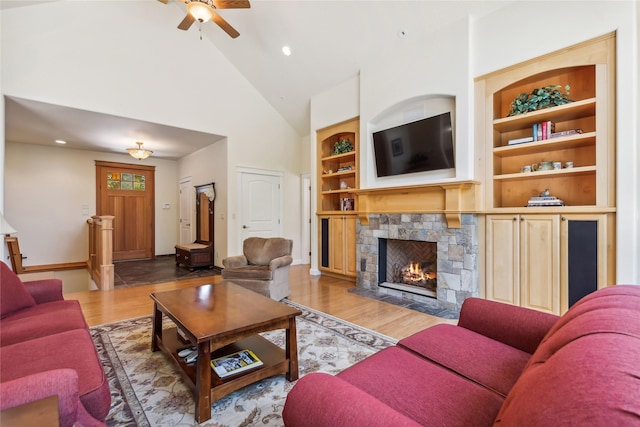 1550 Rolling Ridge Loop, Kalispell, MT 59901 - living area featuring high vaulted ceiling, ceiling fan, a stone fireplace, built in shelves, and wood finished floors