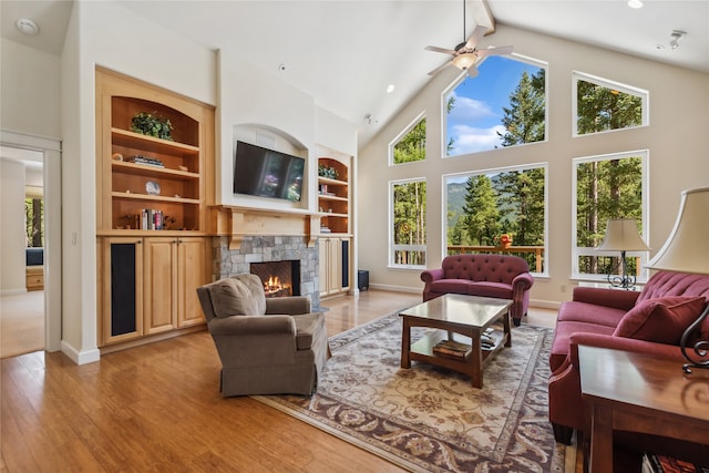 living room with a fireplace, high vaulted ceiling, hardwood / wood-style flooring, and ceiling fan