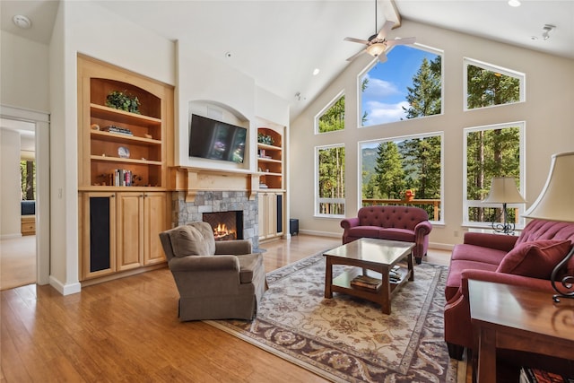 1550 Rolling Ridge Loop, Kalispell, MT 59901 - living area with a stone fireplace, ceiling fan, recessed lighting, light wood-style floors, and high vaulted ceiling