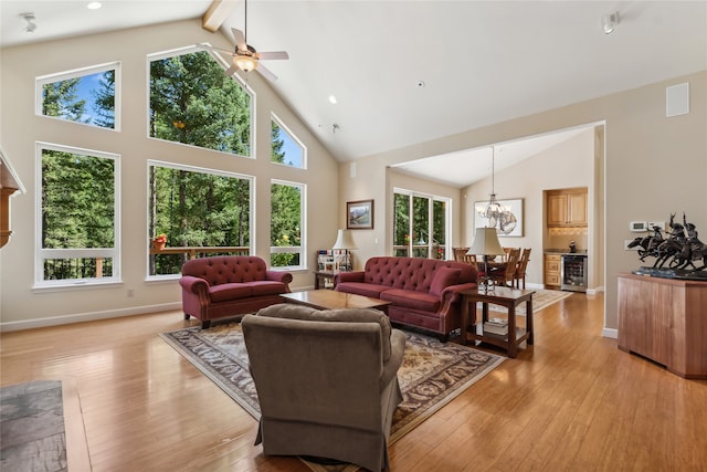 living room with ceiling fan with notable chandelier, beamed ceiling, light hardwood / wood-style flooring, and high vaulted ceiling