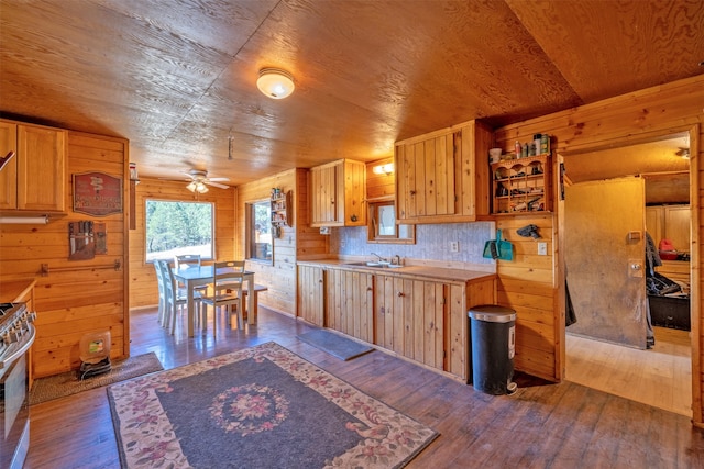 kitchen with wood walls, ceiling fan, decorative backsplash, stainless steel range, and light hardwood / wood-style floors