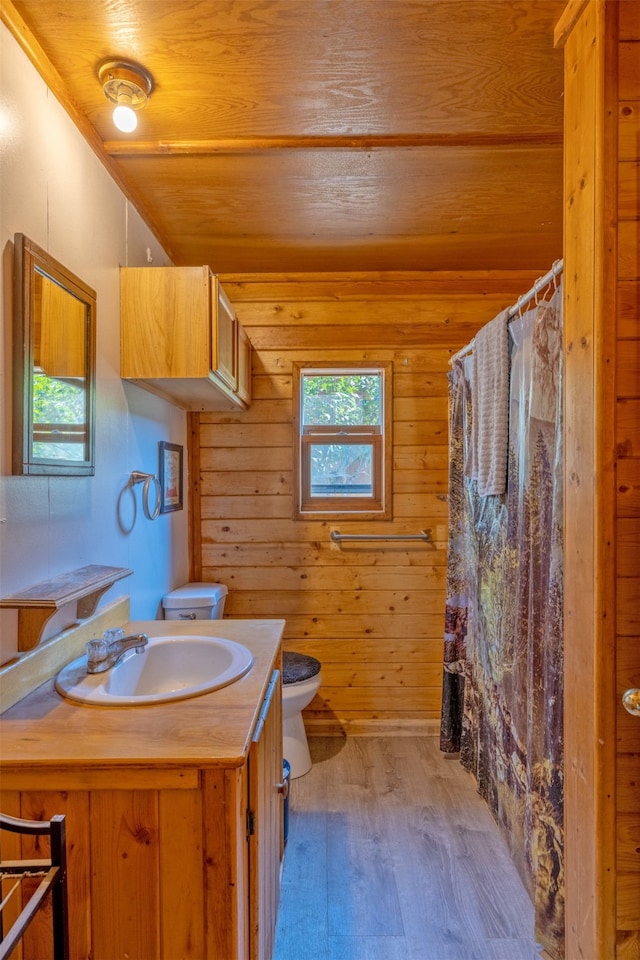 bathroom featuring vanity, wooden walls, wooden ceiling, hardwood / wood-style floors, and toilet