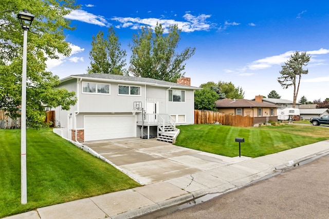 split foyer home with driveway, stucco siding, fence, a front lawn, and brick siding