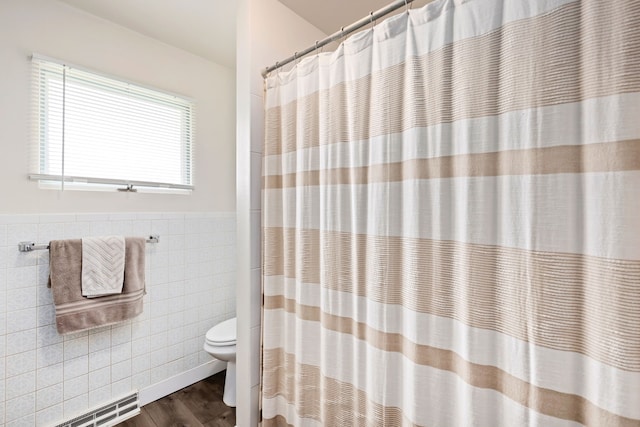 bathroom featuring wainscoting, toilet, a shower with curtain, wood finished floors, and tile walls