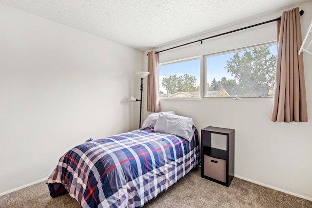 carpeted bedroom featuring a textured ceiling and baseboards