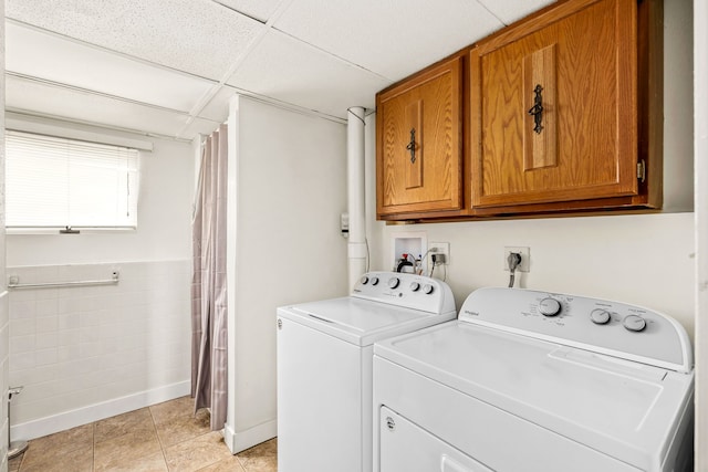 clothes washing area with cabinet space, independent washer and dryer, tile walls, and light tile patterned floors