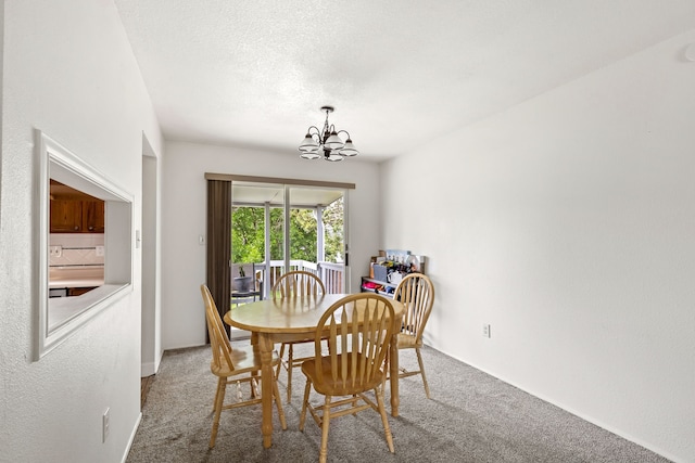 carpeted dining space featuring a notable chandelier and a textured ceiling