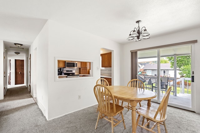 dining room with a chandelier, baseboards, and light colored carpet