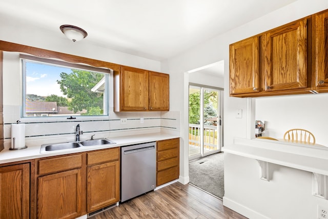 kitchen featuring a healthy amount of sunlight, brown cabinets, a sink, and stainless steel dishwasher