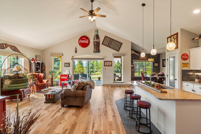 living room featuring high vaulted ceiling, ceiling fan, plenty of natural light, and light hardwood / wood-style flooring