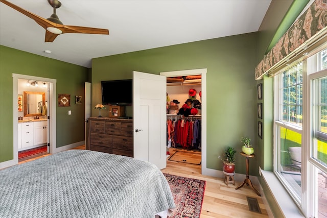 bedroom featuring light wood-type flooring, connected bathroom, ceiling fan, a closet, and a walk in closet