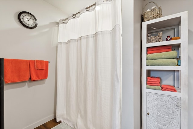 full bathroom with a shower with shower curtain, baseboards, and wood finished floors