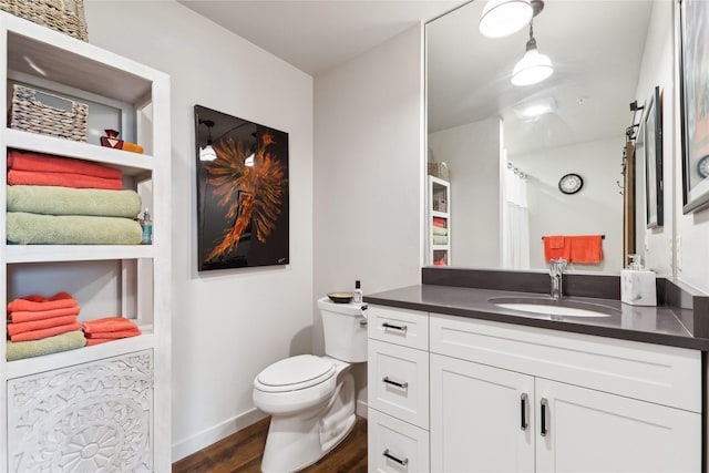 bathroom with wood finished floors, vanity, toilet, and baseboards