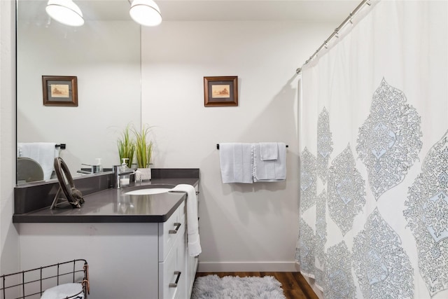 bathroom featuring baseboards, wood finished floors, and vanity