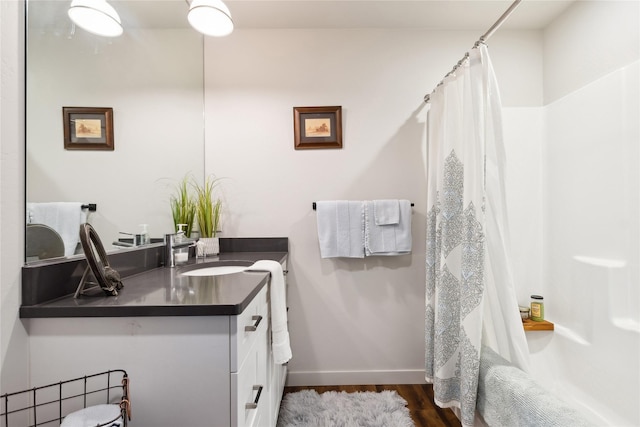 full bathroom with curtained shower, vanity, baseboards, and wood finished floors