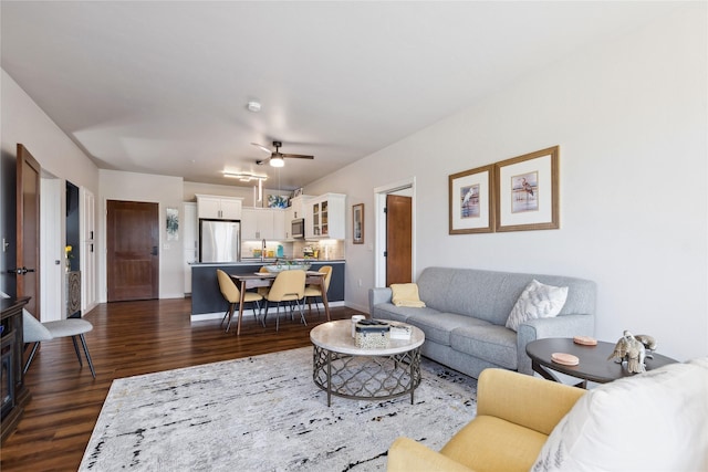 living room featuring a ceiling fan, dark wood-style flooring, and baseboards