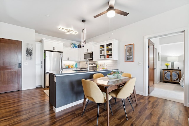 kitchen with tasteful backsplash, dark wood finished floors, glass insert cabinets, stainless steel appliances, and white cabinetry