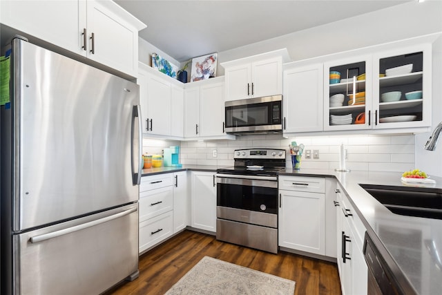 kitchen featuring white cabinets, decorative backsplash, dark wood-style flooring, stainless steel appliances, and a sink