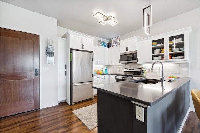 kitchen featuring a peninsula, a sink, white cabinetry, appliances with stainless steel finishes, and dark wood-style floors