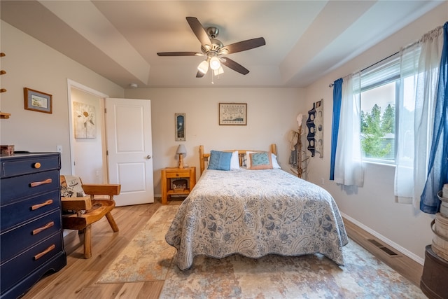 bedroom with a tray ceiling, ceiling fan, and light hardwood / wood-style floors