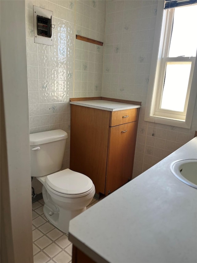 bathroom featuring tile patterned flooring, tile walls, toilet, and vanity