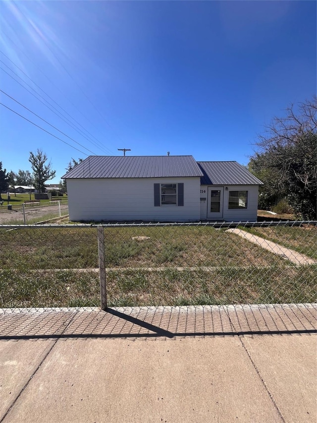 view of front facade with metal roof, a front lawn, and fence