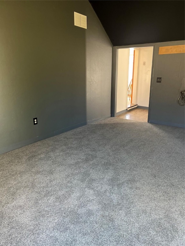 carpeted spare room with visible vents and vaulted ceiling