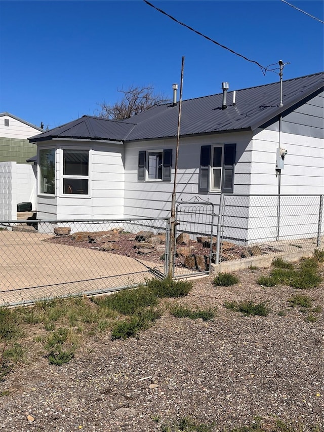 view of side of home featuring metal roof and fence