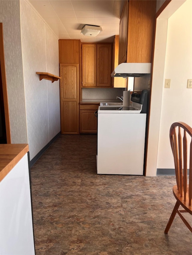 kitchen featuring under cabinet range hood, washer / clothes dryer, range, and brown cabinetry