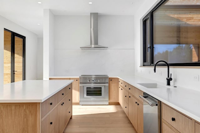 kitchen featuring sink, wall chimney range hood, light brown cabinets, dishwasher, and range