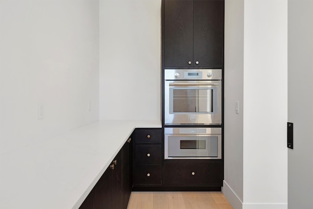 kitchen with double oven and light hardwood / wood-style floors