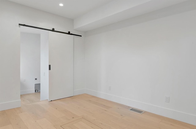 spare room featuring a barn door and light hardwood / wood-style flooring