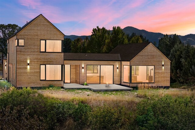 back house at dusk with a mountain view and a patio