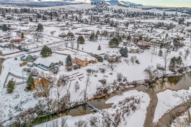 snowy aerial view with a water and mountain view