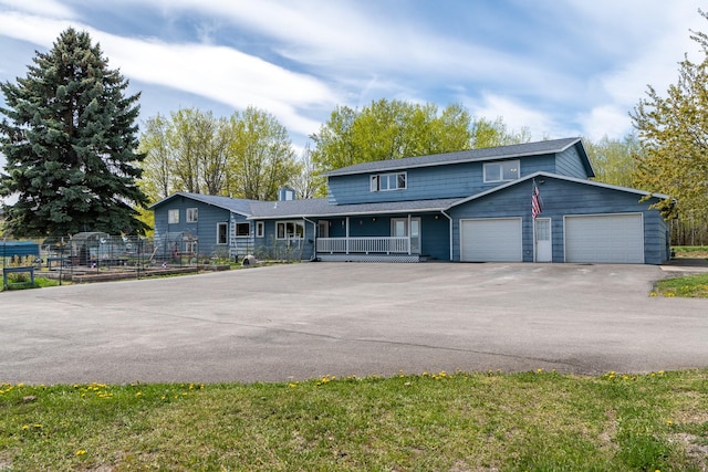 view of front of property with covered porch, asphalt driveway, fence, a garage, and a chimney