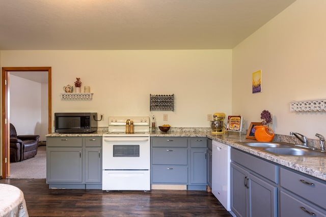 kitchen with white appliances, a sink, dark wood-type flooring, and gray cabinetry