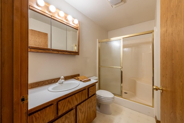 bathroom featuring tile patterned floors, a shower stall, toilet, and vanity