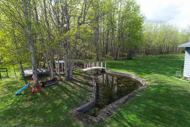 view of green lawn with a wooded view