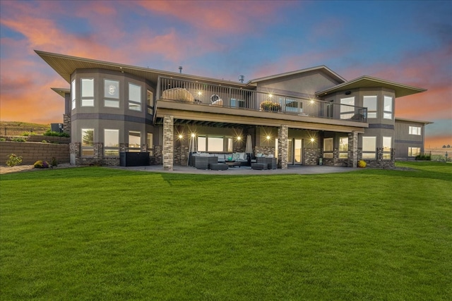 back house at dusk with a lawn, a patio area, an outdoor hangout area, and a balcony