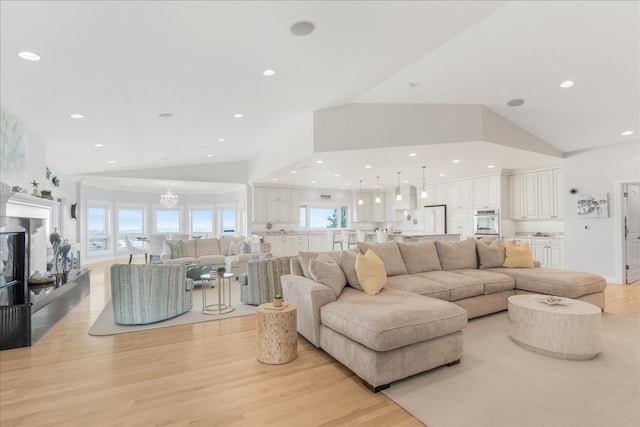 living room with light wood-type flooring, high vaulted ceiling, and an inviting chandelier