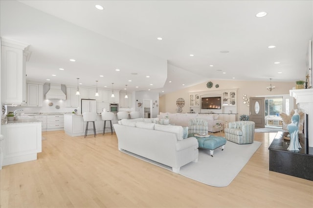 living room with vaulted ceiling, a notable chandelier, and light hardwood / wood-style floors