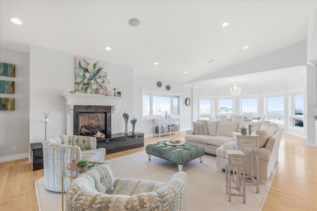 living room with vaulted ceiling, light hardwood / wood-style floors, a chandelier, and a premium fireplace